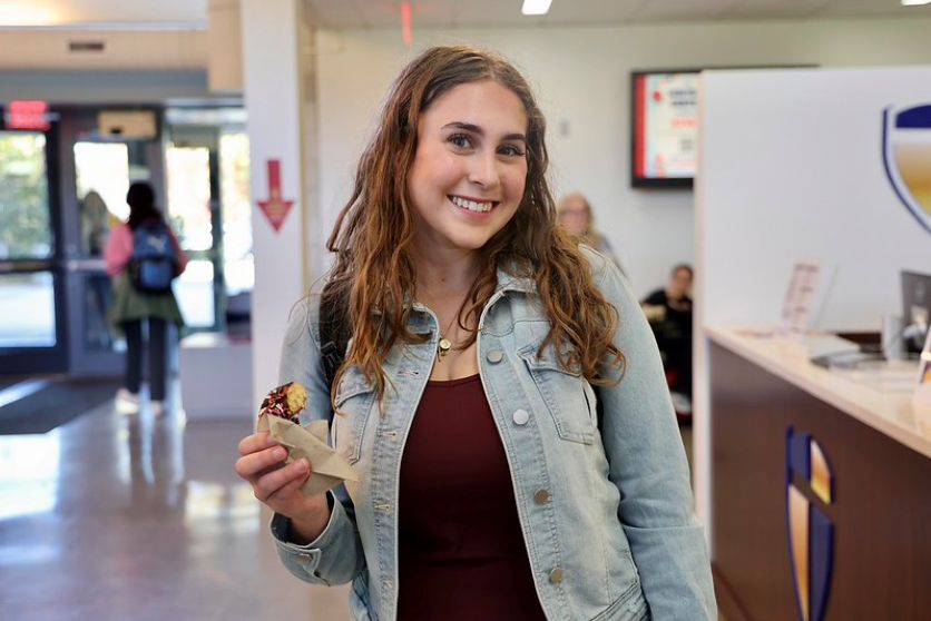 student posing with donut at registration fest
