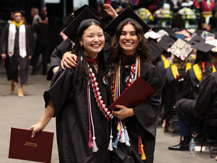 Molloy University graduates smiling as they receive their diplomas 