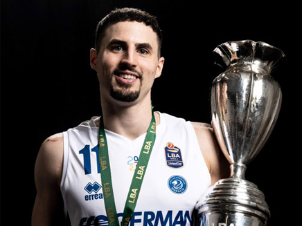Former Molloy basketball star John Petrucelli, holding a large silver trophy and wearing a white jersey with a green medal.