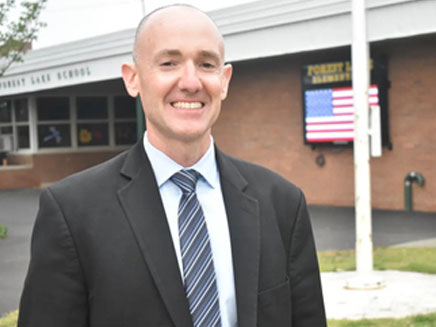 Photo of Thomas Burke in front of his school building