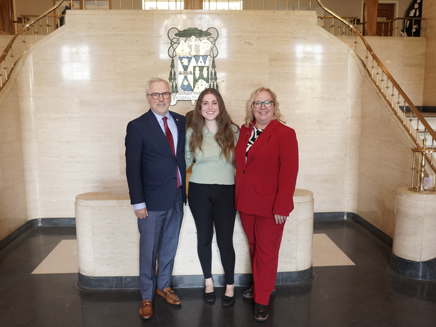 Valedictorian Isabella Schaefer, posed smiling with president and vice president of Molloy University
