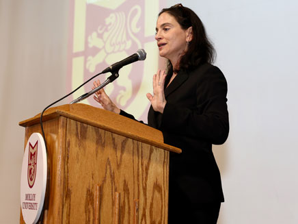 Professor Jennifer Mannino speaking in front of a podium at a Legislative Forum