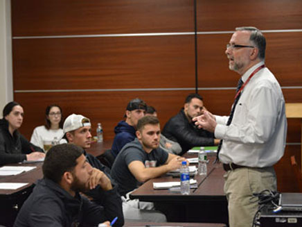 Dr. John Eterno teaching in a classroom full of students at Molloy University.