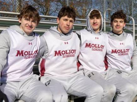 Noah, Owen, Liam and Jake Taylor sitting together with Molloy men's lacrosse jerseys.