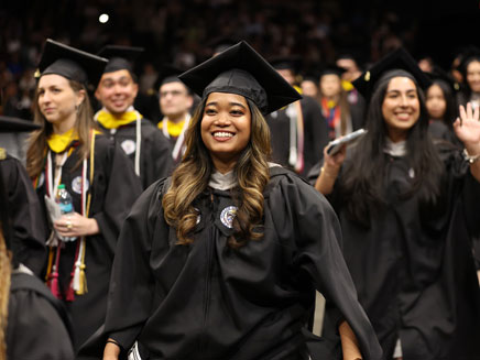 Smiling undergraduate student walking to receive their diploma 