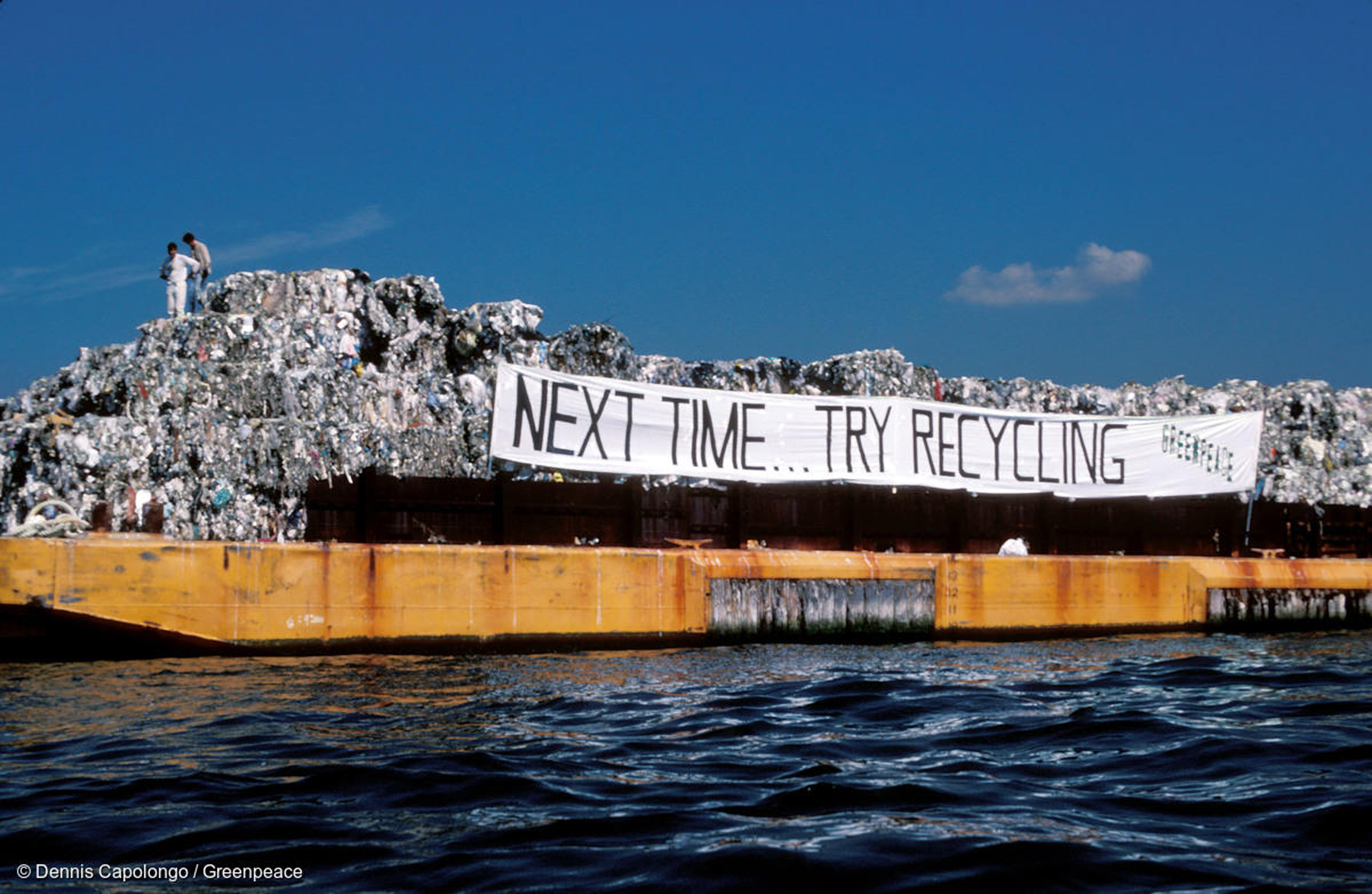 Photo of garbage barge with banner reading "Next Time... Try Recycling Greenpeace"