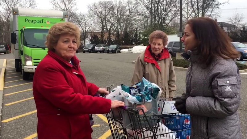 Adrienne Esposito speaking to 2 shoppers with a shapping cart in a parking lot