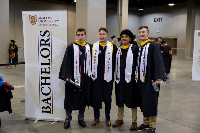 4 Molloy students taking a picture at Commencement